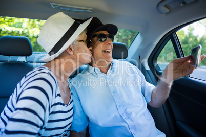 Senior man taking selfie with woman in car