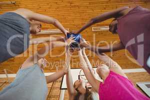 High school kids holding basketball together in the court