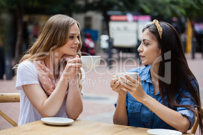 Friends drinking coffee while sitting at sidewalk cafe