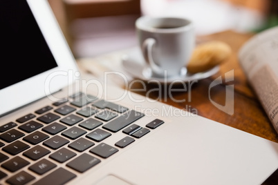 Close up of coffee cup by laptop on wooden table