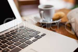 Close up of coffee cup by laptop on wooden table