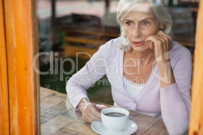 Thoughtful senior woman sitting by table