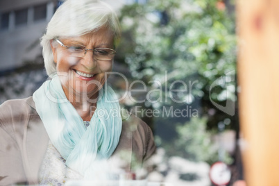 Smiling senior woman standing at cafe shop