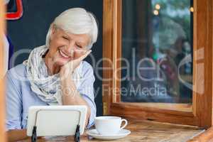 Smiling woman using digital tablet while sitting at table