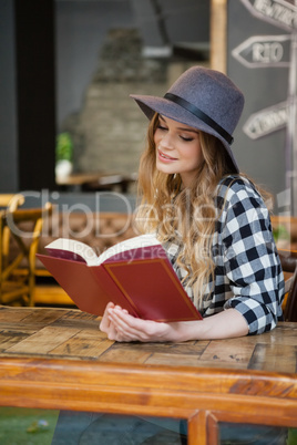 Young beautiful woman wearing hat reading book