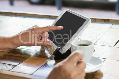 Close up of woman using tablet while drinking coffee
