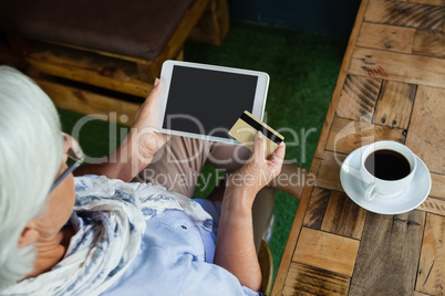High angle view of woman holding tablet and credit card