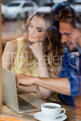 Couple using digital laptop while sitting at cafe shop