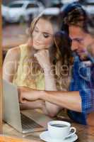 Couple using digital laptop while sitting at cafe shop