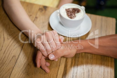 High angle view of couple holding hands by coffee cup
