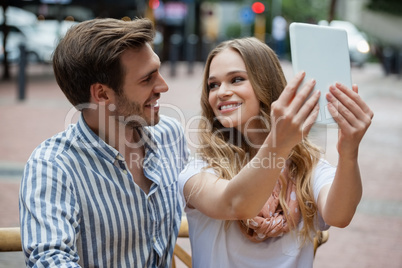 Couple holding digital tablet while sitting at cafe