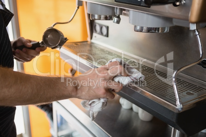 Mid section of waiter cleaning coffeemaker machine