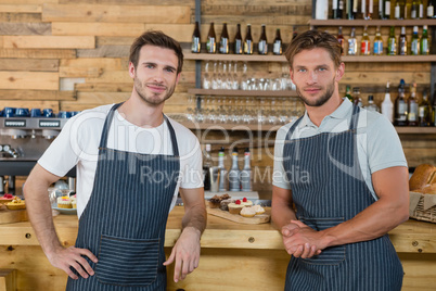 Portrait of smiling waiters standing at counter