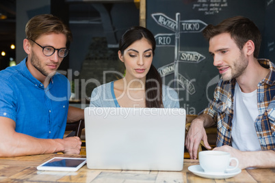 Friends using laptop while having coffee