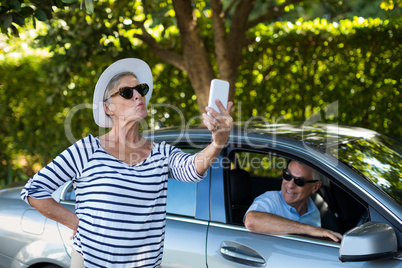 Woman taking selfie with man sitting in car