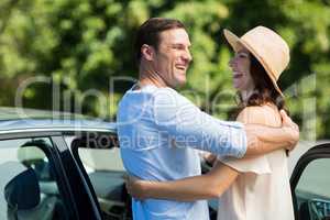 Couple embracing by car on sunny day