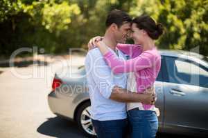 Couple embracing by car on sunny day
