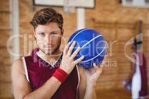 Confident basketball player holding basketball in the court