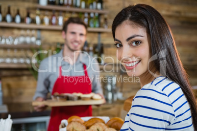 Portrait of smiling woman with waiter standing in background