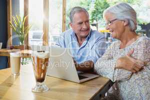 Senior couple interacting while using laptop