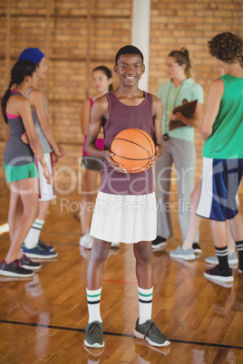 High school boy standing with basketball in the court