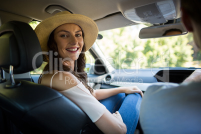 Smiling young woman sitting with man in car