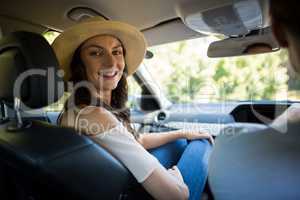 Smiling young woman sitting with man in car