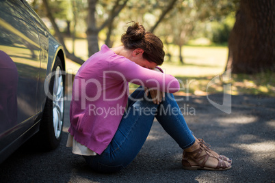 Woman sitting by breakdown car