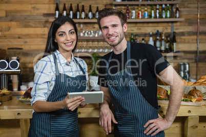 Portrait of waiter and waitresses using digital tablet at counter