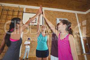 Group of high school kids giving high five in the basketball court