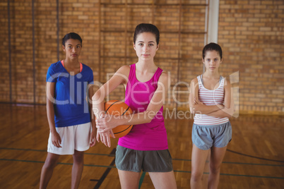 Confident high school girls standing in the court with basketball