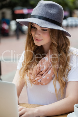 Woman wearing hat using laptop at table