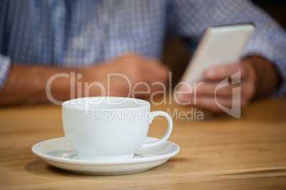 Midsection of senior man using smart phone at table