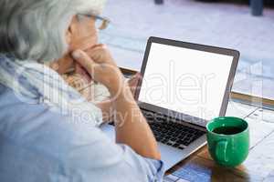 High angle view of thoughtful senior woman using laptop