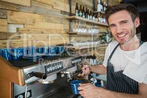 Portrait of smiling waiter preparing coffee from coffee machine