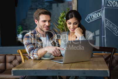 Young couple using laptop while having coffee