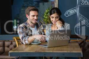 Young couple using laptop while having coffee