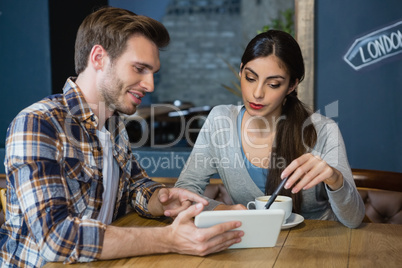 Young couple using digital tablet while having coffee