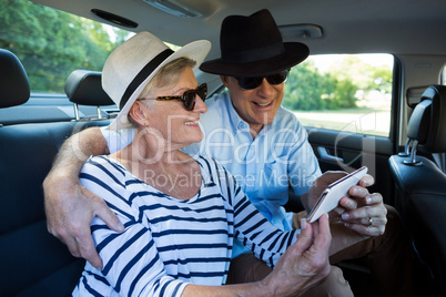Senior couple taking selfie on car back seat