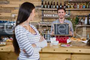Woman standing with arms crossed while waiter holding open signboard