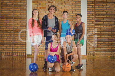 High school kids with basketball standing together in basketball court High school kids with basketball standing together in basketball court