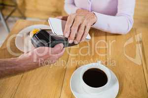 Senior woman making payment through NFC technology on mobile phone