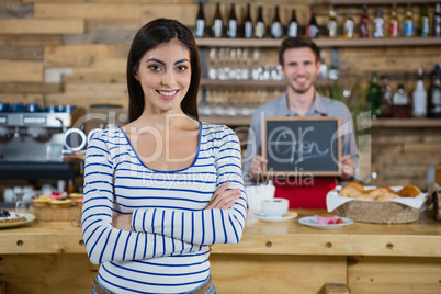 Woman standing with arms crossed while waiter holding open signboard