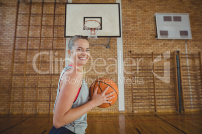 High school girl standing with basketball in the court