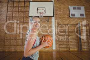 High school girl standing with basketball in the court