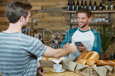 Smiling waiter receiving credit card of customer for payment at counter