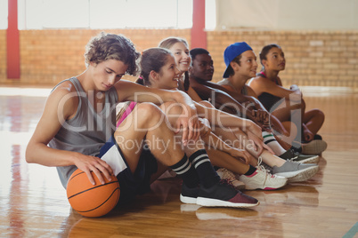 High school kids sitting on the floor in basketball court