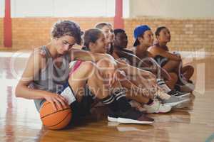 High school kids sitting on the floor in basketball court