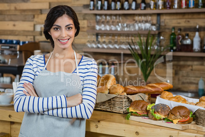 Portrait of waitress standing with arms crossed at counter