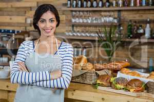 Portrait of waitress standing with arms crossed at counter